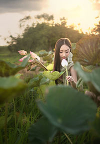 Woman holding flowering plants on field