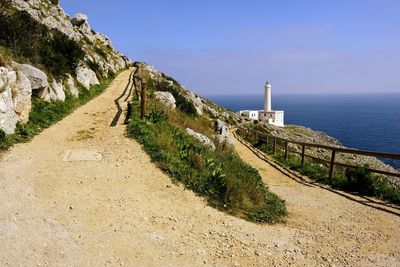 Footpath on mountains by sea against blue sky