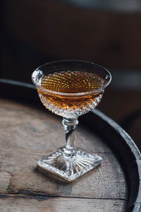 Whiskey cocktail in vintage hobnail glass atop wooden barrel