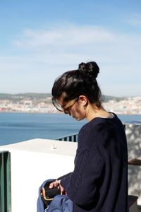 Close-up of young woman standing at building terrace against sky