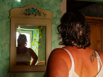Rear view of shirtless woman sitting at home