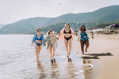 Portrait of smiling friends standing at beach