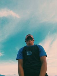 Low angle view of young man looking away against sky