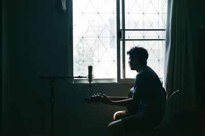 Side view of young man sitting at home