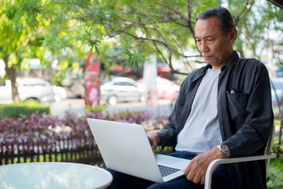 Man using laptop while sitting outdoors