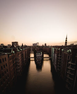 Bridge over river amidst buildings in city against clear sky