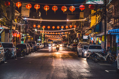 Illuminated street amidst buildings in city at night