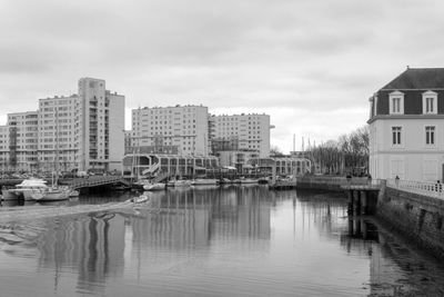 Buildings by river against sky in city