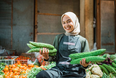 Portrait of young woman holding vegetables at market