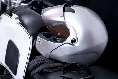 Close-up of helmet and sunglasses on motorcycle against black background
