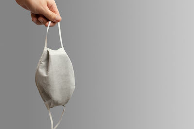 Close-up of hand holding hanging over white background