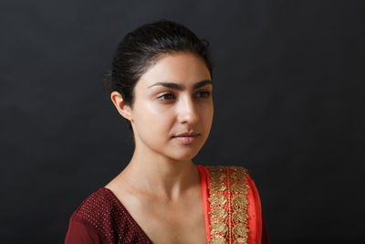 Young woman standing against black background