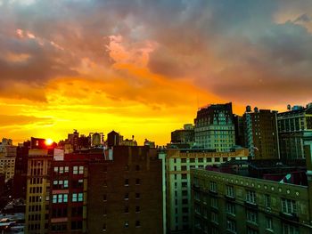 Buildings against dramatic sky during sunset