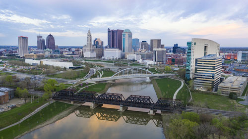 Bridge over river by buildings against sky in city