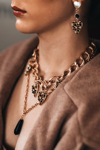 Golden chain hanging on a woman's neck and an earring in the shape of a heart. beautiful  jewelry