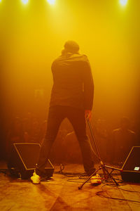 Rear view of man singing on stage in front of audience