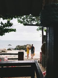 People standing by sea against sky
