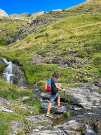 A young man crossing a wild river in pyrenees mountains