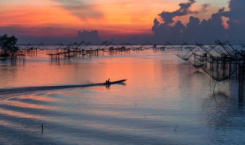 Silhouette boats in sea against sky during sunset