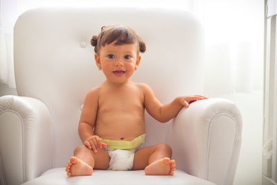 Portrait of smiling boy sitting on sofa at home