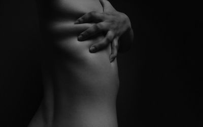 Midsection of topless teenage girl over black background