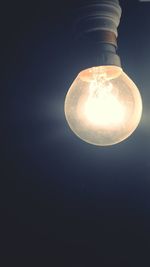Low angle view of lit light bulb at night
