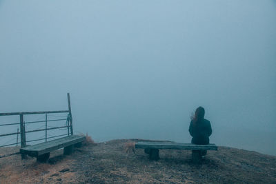 Woman sitting by sea against sky