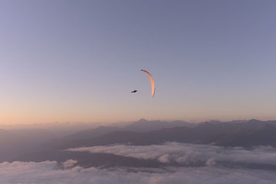 Person paragliding against sky during sunset