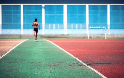 Rear view of female athlete running on sports track