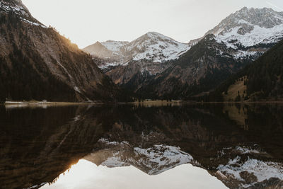 Scenic view of lake by snowcapped mountains against sky