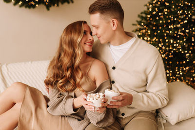 A couple in love hugging and relaxing on a christmas holiday in the decorated interior of the house