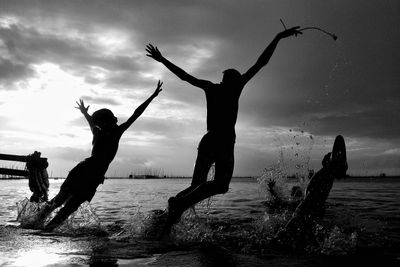 Silhouette people enjoying in river against sky