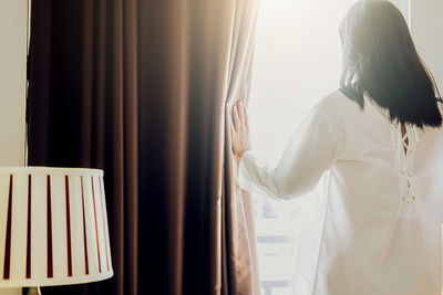 Rear view of woman standing at home