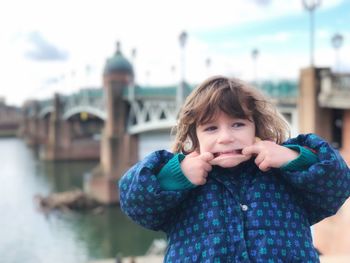 Close-up of happy girl standing against river in city