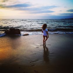 Girl walking at beach against sky