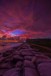 Scenic view of beach against dramatic sky during sunset