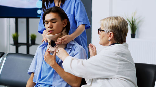 Smiling young woman looking away while standing in hospital