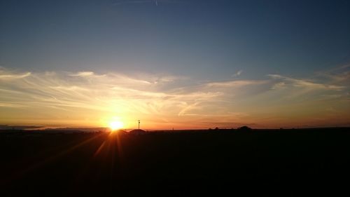 Scenic view of silhouette field against sky at sunset