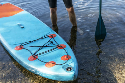 Man faceless with stand up paddleboard blue sup o water lake with paddle male legs active lifestyle 