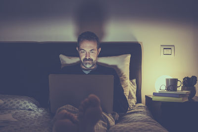 Young man using mobile phone while sitting on sofa at home