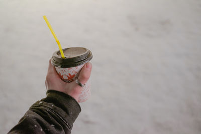 Paper cup in hand with you on the background of cold snow, winter period, hot coffee drink on the 