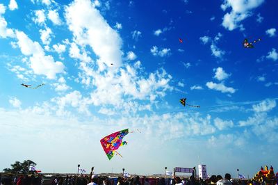 Low angle view of people paragliding against sky