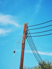 Low angle view of electricity pylon against clear blue sky