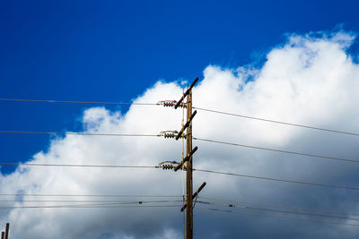 Low angle view of electricity pylon against blue sky