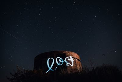 Low angle view of information sign against sky at night