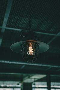 Close-up of illuminated light bulb hanging from ceiling