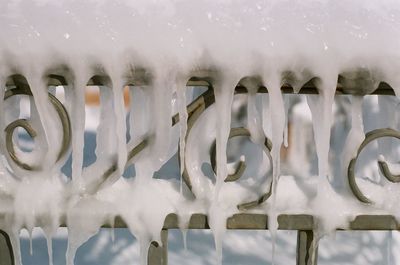 Close-up of snow on metallic gate during winter