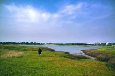 Woman on a beautiful open field against sky beside a lake