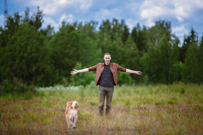 Rear view of man with dog on field