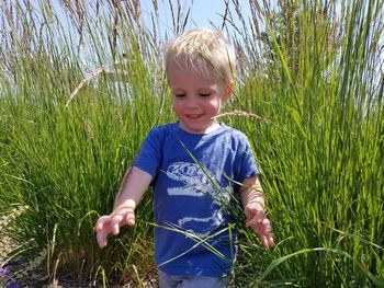 Cute boy amidst grass in field